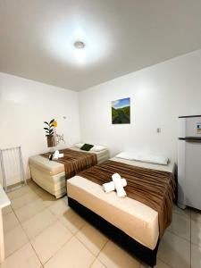 a hotel room with two beds and a refrigerator at Pousada Marajó For You in Soure
