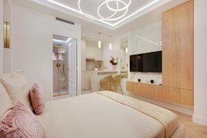 a white bedroom with a large bed and a tv at Bretagne Mairie du 3e in Paris