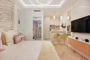 a white bedroom with a large bed and a kitchen at Bretagne Mairie du 3e in Paris +4 photos