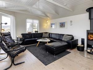 a living room with a black leather couch and chairs at 7 person holiday home in L kken in Løkken
