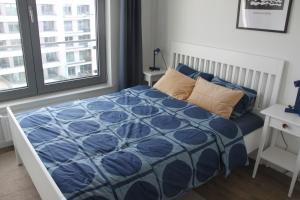 a bedroom with a bed with a blue comforter and a window at APARTAMENTY Z MORZA I MARZEŃ in Gdynia