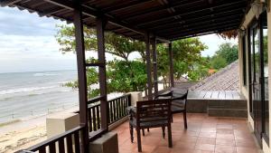 een veranda met een tafel en stoelen op het strand bij Tropical House Beach Bungalow in Kesembu