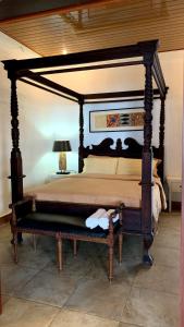 - un lit à baldaquin avec un banc dans une chambre dans l'établissement Tropical House Beach Bungalow, à Kesembu