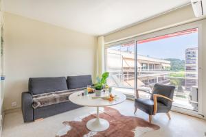 ein Wohnzimmer mit einem Sofa und einem Tisch in der Unterkunft Spacieux appartement Climatisé, lumineux, Grand Balcon, dernier étage au calme dans le parc de la Torse à 10mn à pied du centre ville in Aix-en-Provence