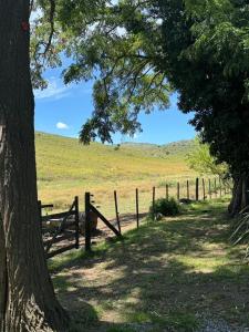 una valla de madera en un campo con un árbol en Casa quinta Don bosco en Tandil