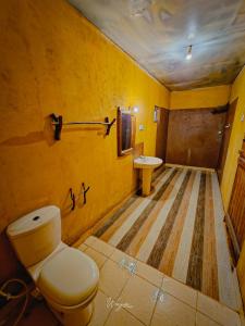 bagno giallo con servizi igienici e lavandino di River Edge Safari Cottage a Udawalawe