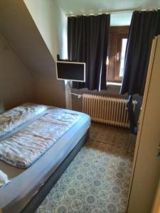 um pequeno quarto com uma cama e uma cadeira em MB City Pension em Nurembergue