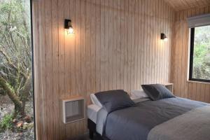 a bedroom with a bed in a wooden wall at Impressive Don Santiago Cabin, Chilean Patagonia. in Chaitén