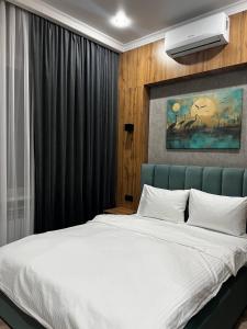 a bedroom with a large white bed with a blue headboard at Sunrise Hotel in Taldykorgan