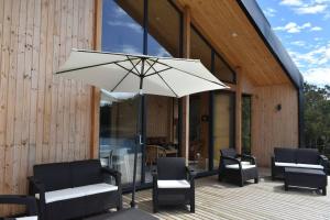 a patio with chairs and an umbrella on a deck at Impressive Don Santiago Cabin, Chilean Patagonia. in Chaitén