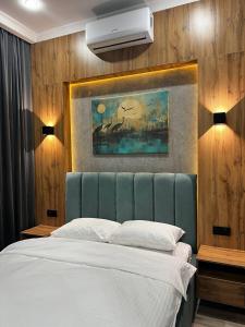 1 dormitorio con 1 cama y una pintura en la pared en Sunrise Hotel, en Taldykorgan