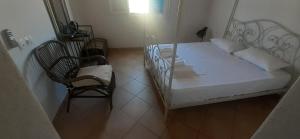 a bedroom with a white bed and a chair at Hotel Posidonion in Koufonisia