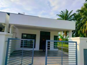 a house with a gate in front of it at Aiman's Rose HomeStay in Teluk Panglima Garang