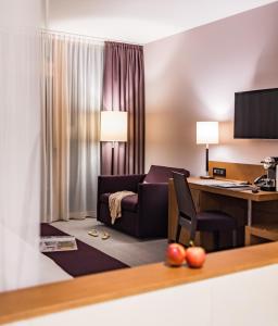 a hotel room with a desk and a couch at Deltapark Vitalresort**** in Thun