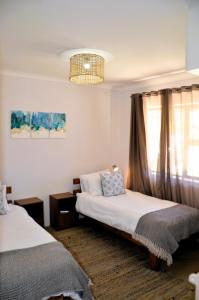 ein Schlafzimmer mit zwei Betten und einem Fenster in der Unterkunft The Beach Cottage Betty's Bay in Bettyʼs Bay