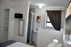 ein Badezimmer mit einem Bett, einem Waschbecken und einem Spiegel in der Unterkunft The Beach Cottage Betty's Bay in Bettyʼs Bay