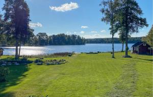 a large grassy field next to a lake at Lovely Home In Ormaryd With Sauna in Ormaryd