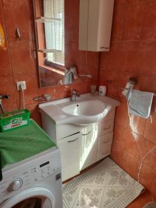 a bathroom with a washing machine and a sink at Villa Artemida apartman in Kulen Vakuf
