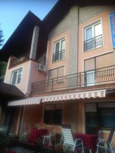 a building with chairs sitting outside of it at Villa Artemida apartman in Kulen Vakuf