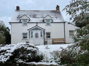 uma casa branca com um banco na neve em Rose Cottage room Bee Happy em Newquay