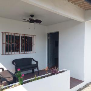 a patio with a black chair and a ceiling fan at Casa de playa in Isla Grande