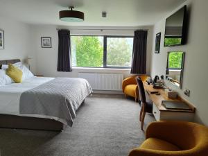 Camden Lodge B&B and Cottage Brecon في بريكون: غرفة نوم بسرير ومكتب وكرسيين