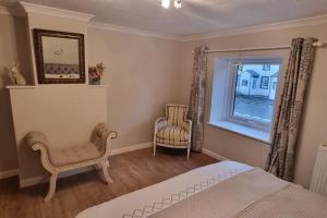 um quarto com uma cama, 2 cadeiras e uma janela em Luxury Lake District Retreat above Ennerdale em Kirkland