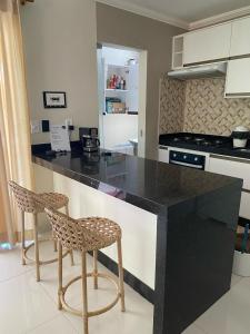 a kitchen with a black counter and two bar stools at Casa da lagoa in Porto Seguro