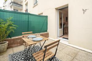 un patio con mesa, sillas y una pantalla verde en Studio Centre-Ville avec Terrasse et Parking Sécurisé Gratuit, en Nantes