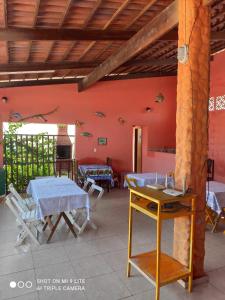 una habitación con mesas y sillas y una pared roja en Pousada Galinhos en Galinhos