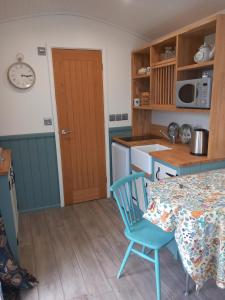 a kitchen with a table and a blue chair at The Mad Hatter's Hut in Carlisle