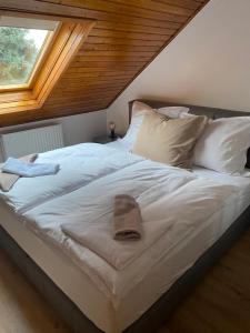 ein Bett mit weißer Bettwäsche und Kissen sowie einem Fenster in der Unterkunft Erelia Cottage in Bük
