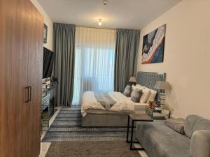 een slaapkamer met een bed en een bank bij Beautiful Cozy Studio (Masdar City) in Al Qurayyah