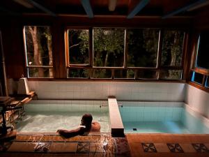 un hombre está sentado en una piscina en Cabañas japonesas en el bosque KURO y AKA, en Valdivia