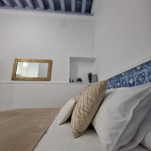 1 dormitorio con cama con almohadas y espejo en Loft del Capataz, en San Fernando