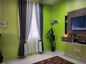 uma sala de estar com paredes verdes e uma janela em Ct HOMESTAY em Changlun