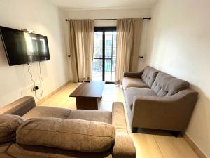 ein Wohnzimmer mit 2 Sofas und einem Flachbild-TV in der Unterkunft Forest View Apartments in Kololi