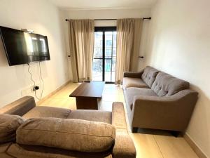 a living room with two couches and a flat screen tv at Forest View Apartments in Kololi