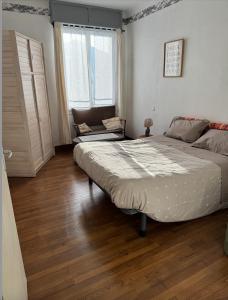 a bedroom with a large bed and a chair at Appartement Sabatier T4 avec terrasse et jardin in Carcassonne