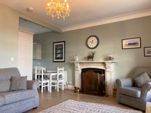 a living room with a fireplace and a clock on the wall at Tonn Ruray Sea View Luxury 2 Bed Apartment in Dundrum