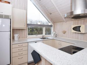 a kitchen with white cabinets and a sink and a window at 9 person holiday home in Hemmet in Falen