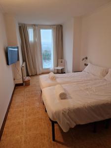 two beds in a hotel room with a window at Pensión Aussie II in San Sebastián