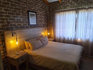 a bedroom with a bed with a brick wall at Numbi Hills Self-Catering in Hazyview