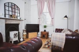 uma sala de estar com um sofá de couro e uma televisão em Spacious and Cosy House for 6 em Rochester