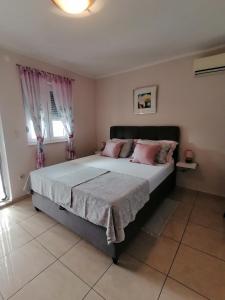 a bedroom with a large bed with pink pillows at Apartmani Marijana in Lozovac