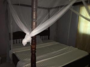 una cama con dosel y una cortina blanca con dosel. en Tropical paradise en Mombasa