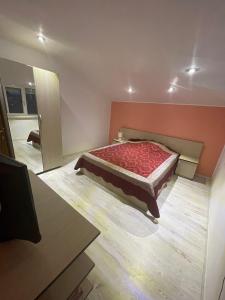 a bedroom with a bed with a red comforter at Casa Croitoru in Mangalia