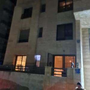 Un edificio con ventanas y un hombre parado frente a él. en 2bd apartment 32, en Amán 2 fotos más