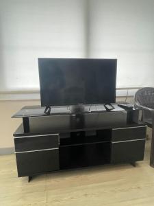 um centro de entretenimento preto com uma televisão de ecrã plano por cima em LuxuryHome em Seyhan