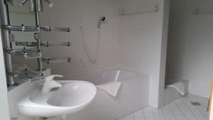 een witte badkamer met een wastafel en een douche bij LebensART in Hautzenbichl